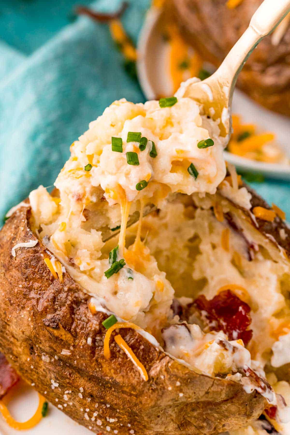A fork scooping the inside of a baked potato out.