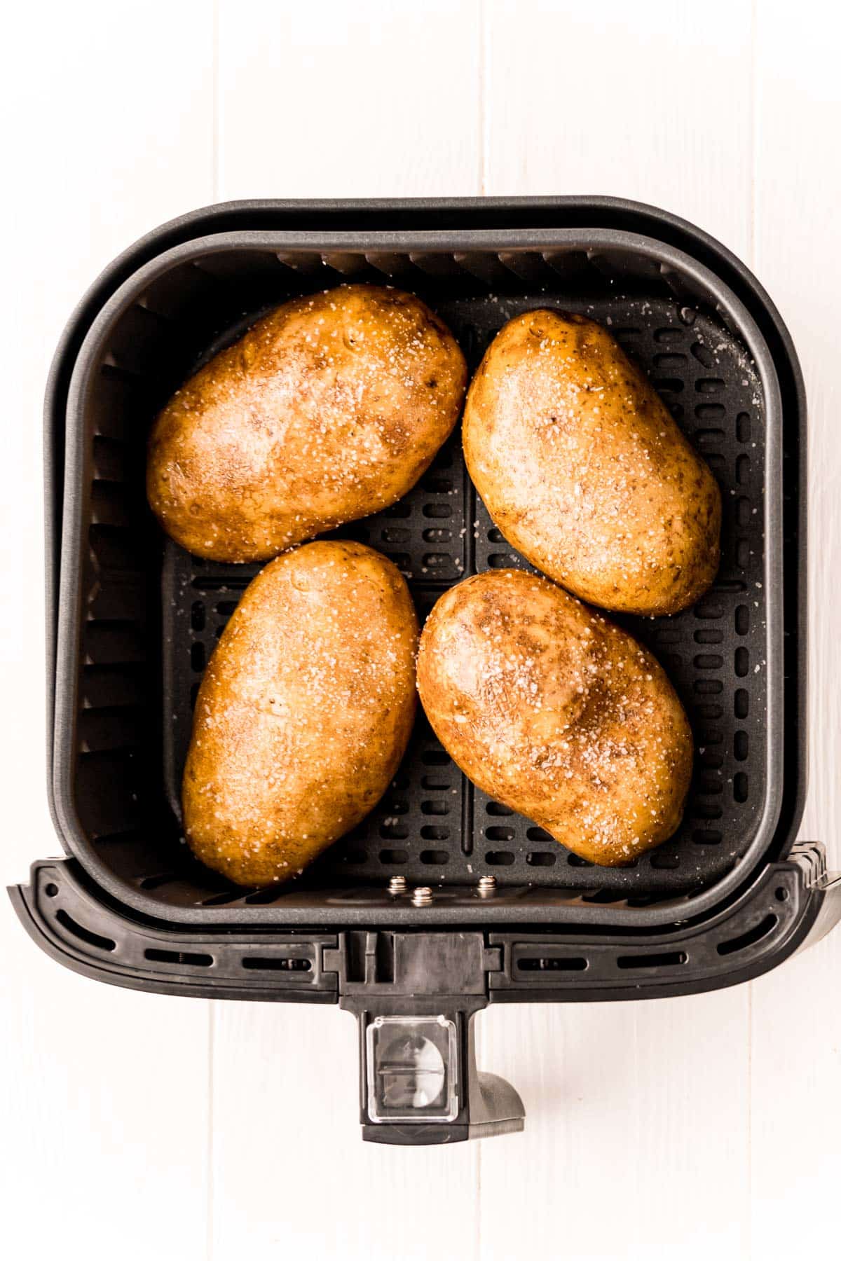 Overhead photo of an air fryer basket with potatoes in it.
