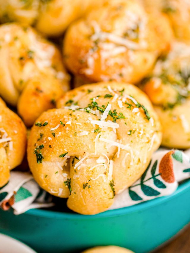 Close up photo of garlic knots in a teal bowl.