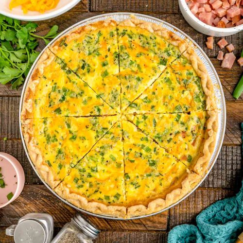 Overhead photo of ham and cheese quiche on a wooden table.