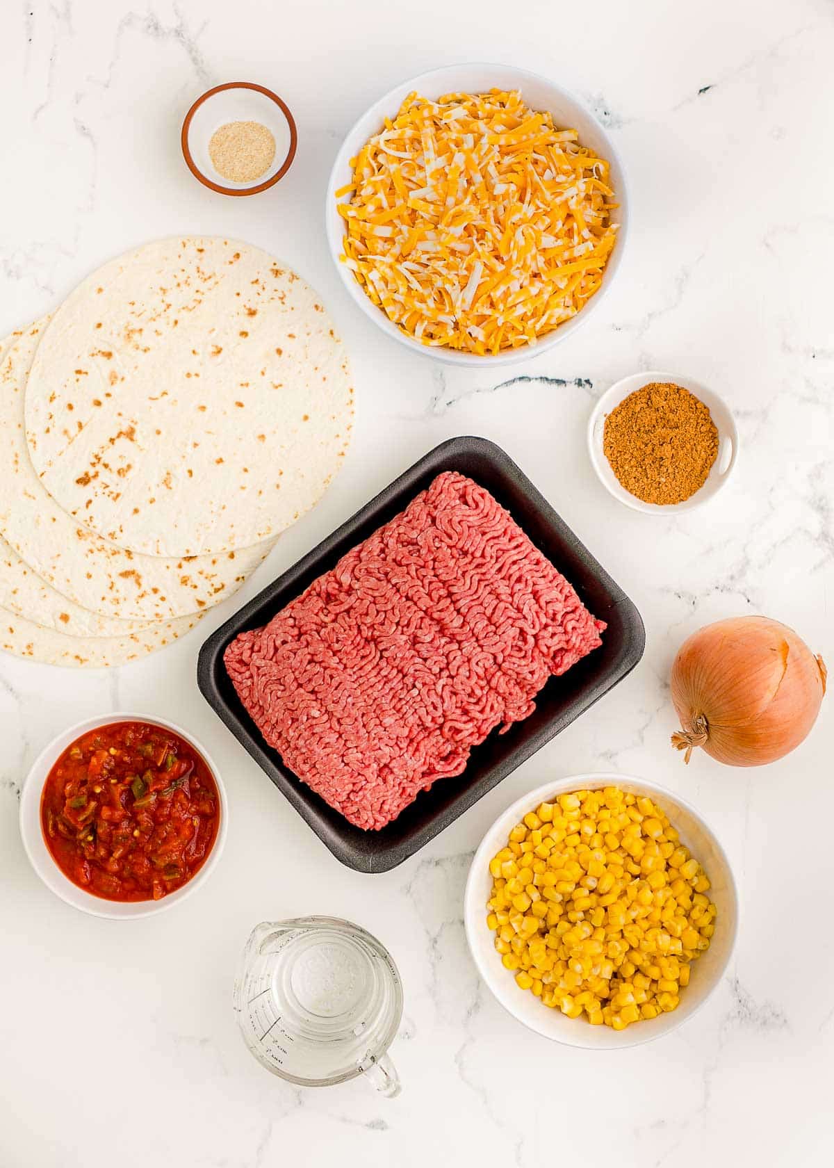 Ingredients to make layered taco pie on a white table.