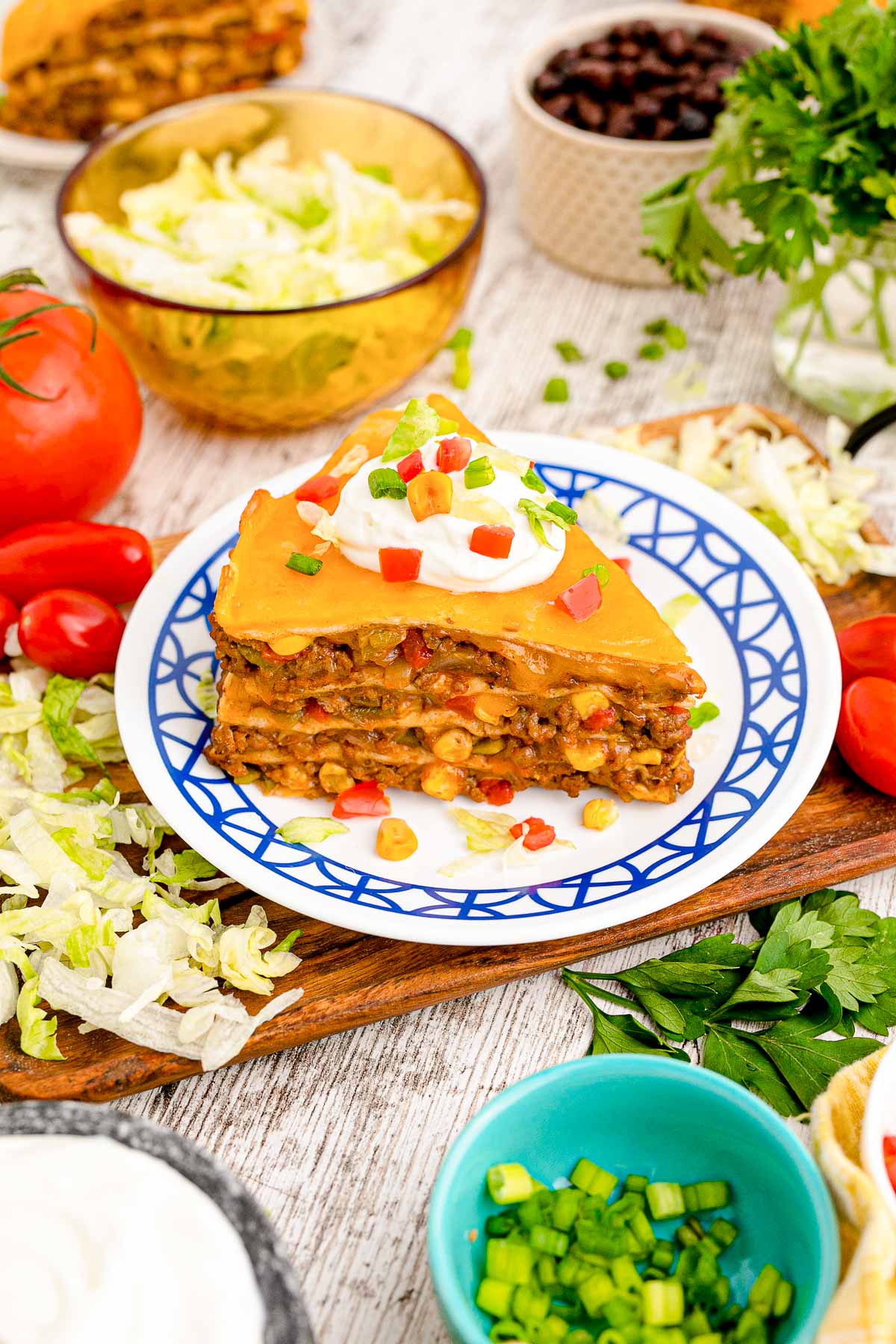 A slice of taco pie on a white and blue plate on a wooden serving tray.