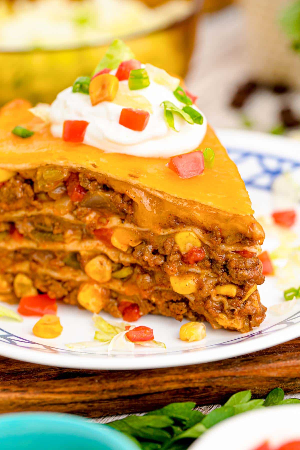 Close up of a slice of taco pie on a white and blue plate.