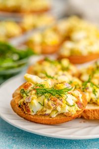 Close up of a crostini topped with bacon egg salad on a plate.