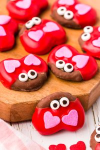 Peanut butter pretzel love bugs for valentine's day on a wooden board.