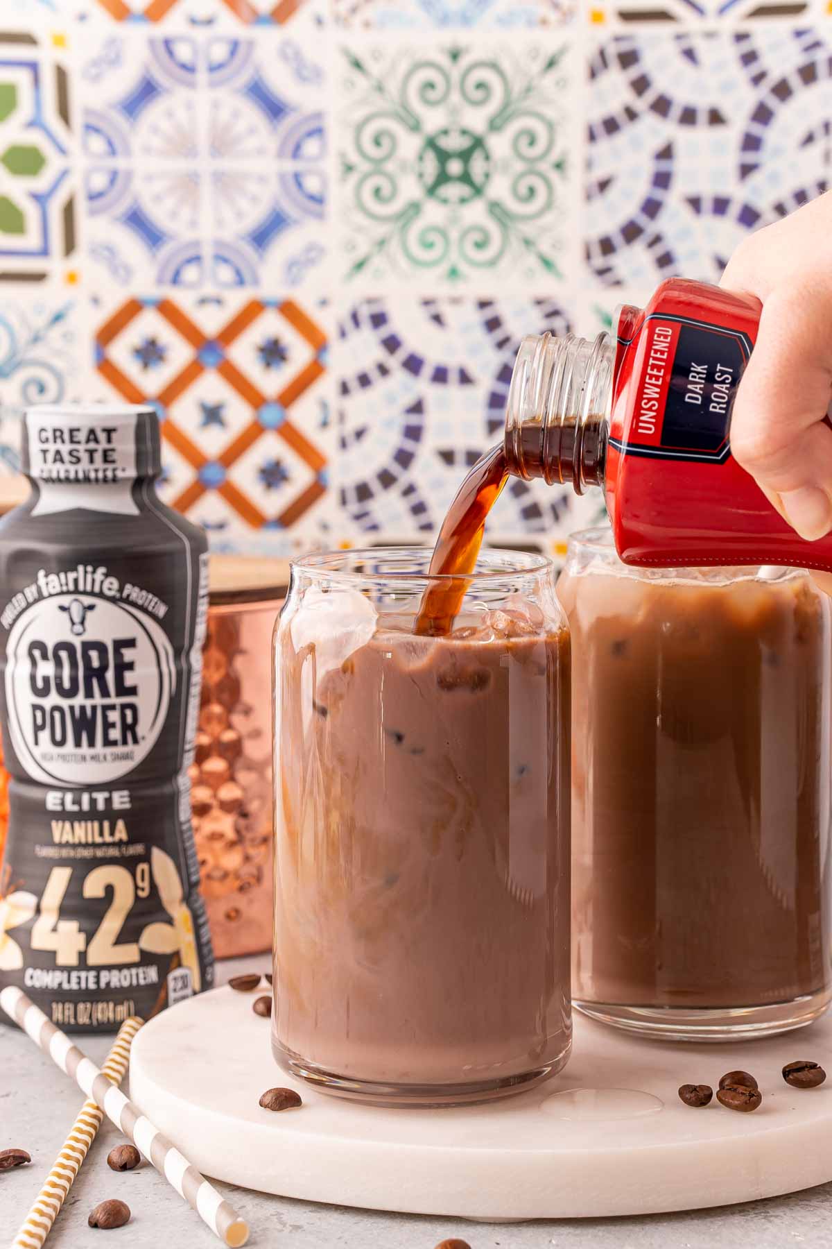 Cold brew coffee being poured into a glass with a chocolate protein shake to make proffee.