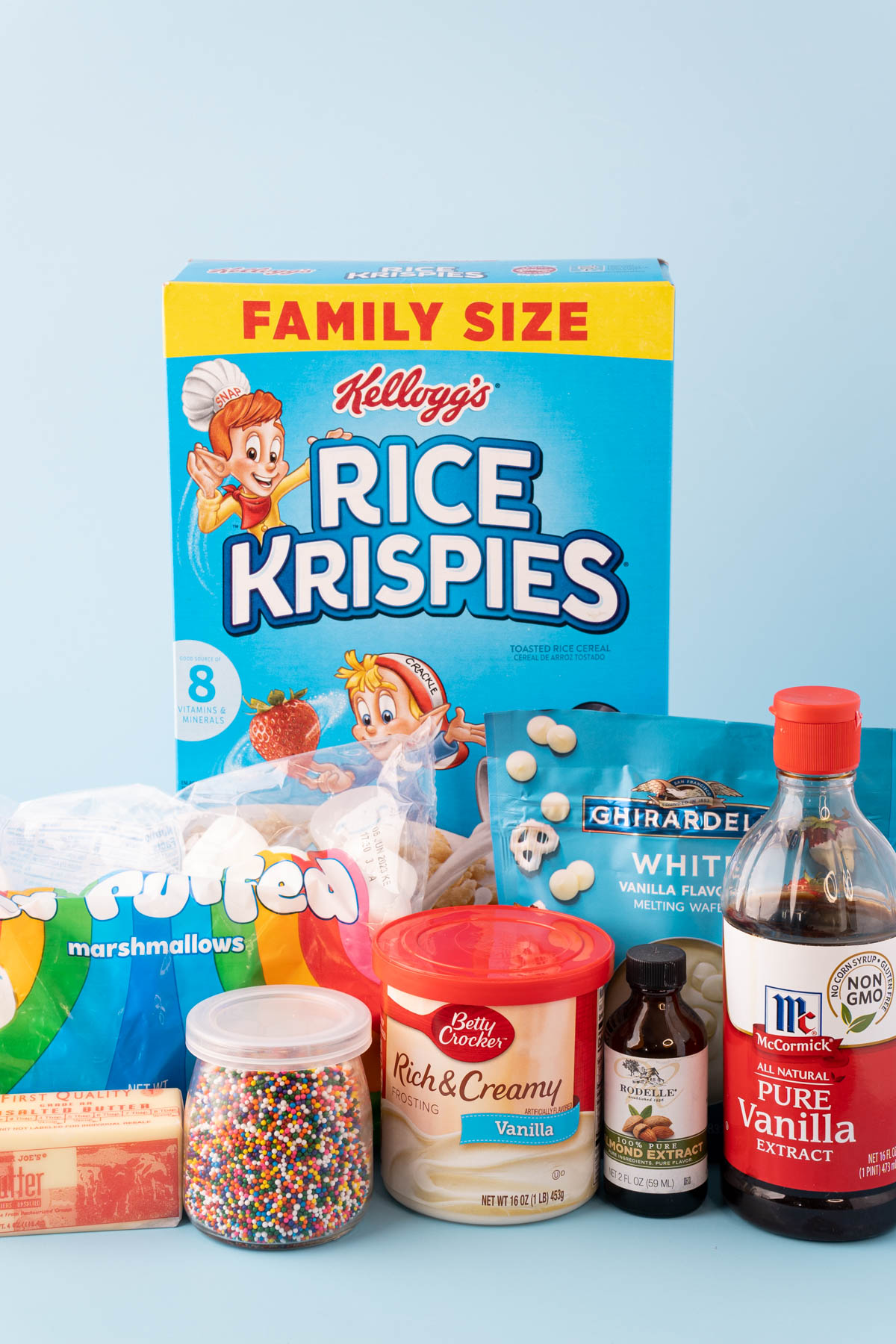 Ingredients to make birthday cake rice krispie treats on a blue table.