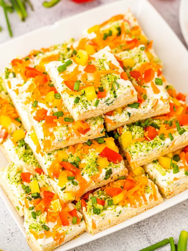 A white serving platter filled with veggie pizza squares for serving.