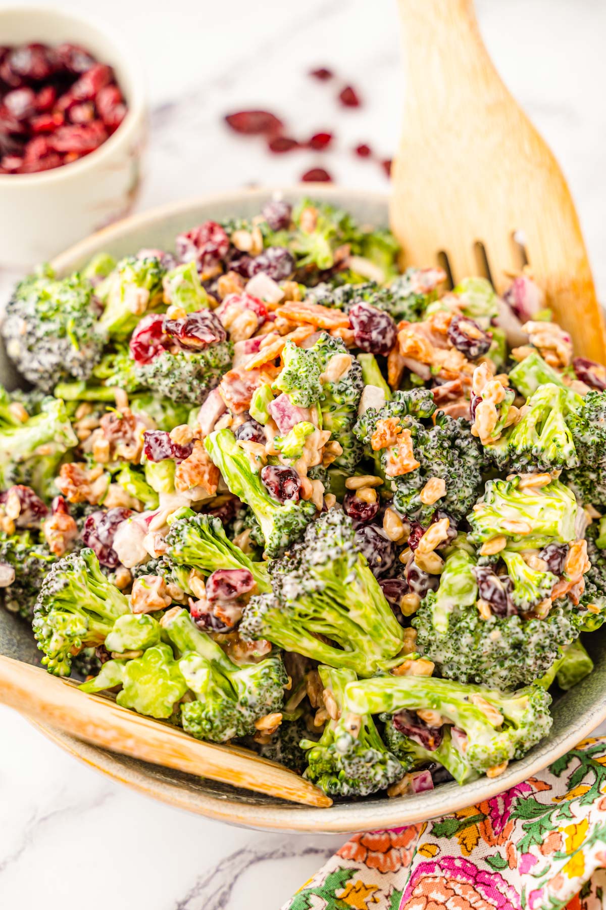 A bowl of broccoli salad with salad spoons.