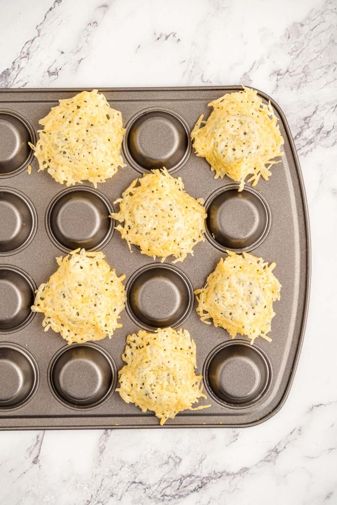 Melted parmesan rounds  laid over the bottom of a mini muffin tin to shape them into cups.