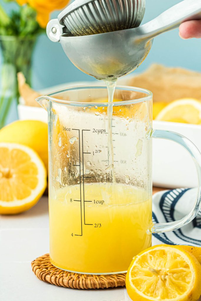 Lemon juice being squeezed into a measuring cup.