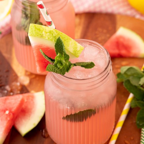 A mason jar filled with watermelon mint lemonade on a wooden board.