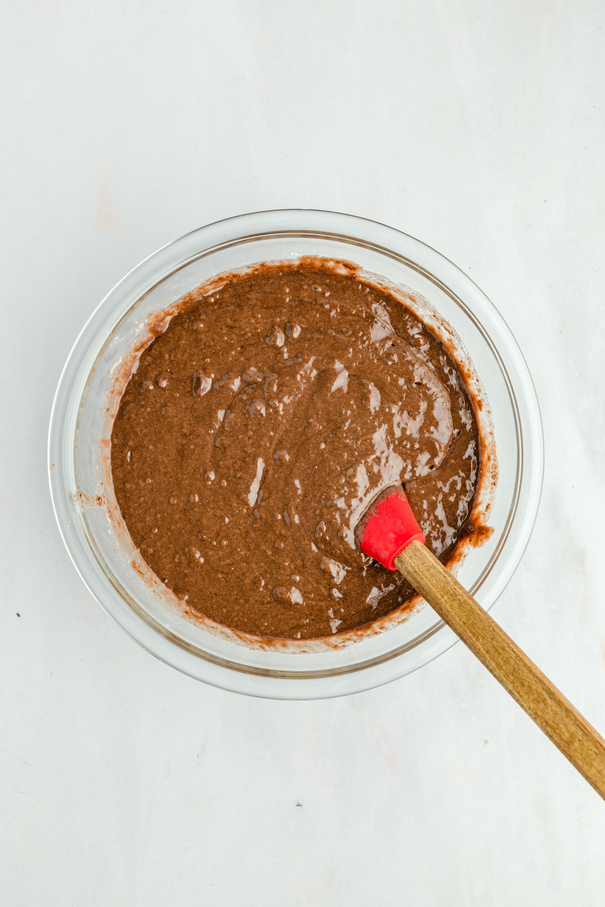 chocolate cupcake batter in a bowl with a spatula mixing it.