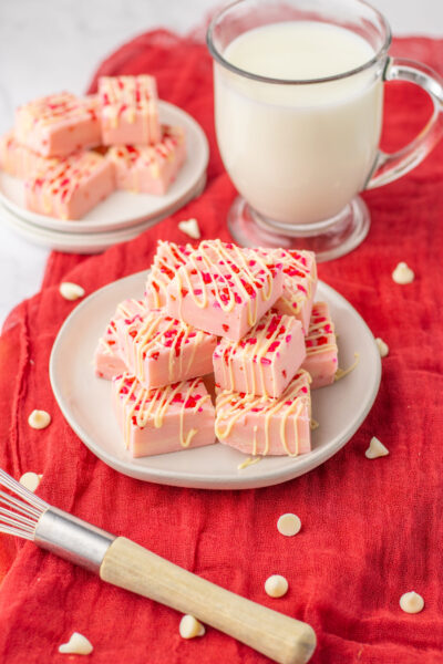 valentines sugar cookie fudge on a white plate with a glass of milk.