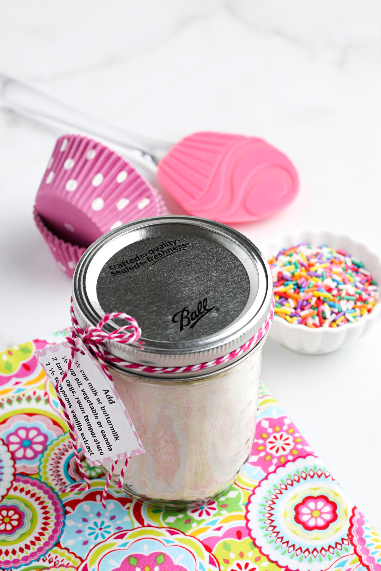 homemade cake mix in a mason jar on a napkin with sprinkles in the background